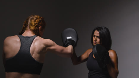 Studioaufnahme-Von-Zwei-Reifen-Frauen-In-Fitnesskleidung,-Die-Gemeinsam-Boxen-Und-Sparring-Trainieren-4